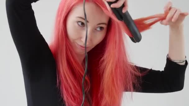 Hår-och frisör koncept. Ung kvinna med rött hår skapar en frisyr med ett strykjärn eller tång — Stockvideo