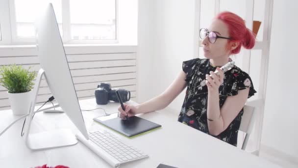 Editor de fotos con trabajos de pelo de color utiliza gráficos tableta en una computadora y fuma vapor — Vídeo de stock