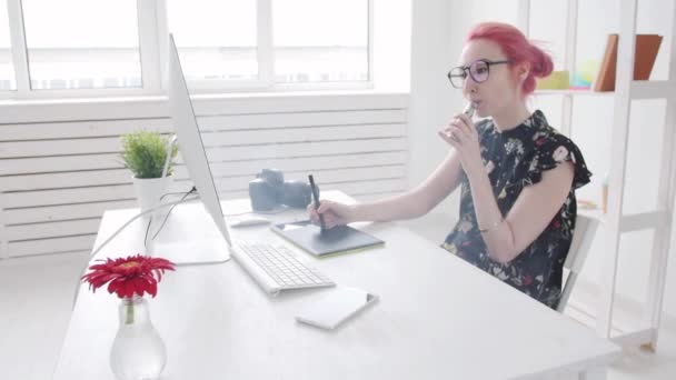 Photo editor with colored hair works used graphics tablet at a computer and smokes vape — Stock Video