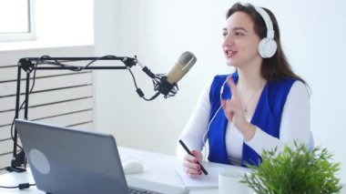 Akış ve yayın kavramı. Kulaklık takan ve online radyo istasyonunda konuşan genç kadın