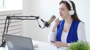 Akış ve yayın kavramı. Kulaklık takan ve online radyo istasyonunda konuşan genç kadın