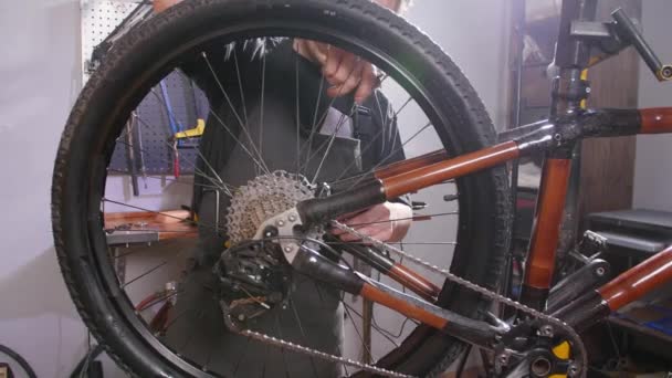 Fietsservice concept. Een jonge man repareert en onderhoudt een fiets in de workshop — Stockvideo