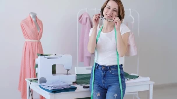 Konzept von Hobby und Kleinunternehmen. schöne junge Schneiderin lächelt in die Kamera — Stockvideo