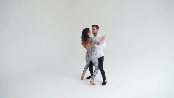 Concepto de amor, relaciones y baile social. Joven hermosa pareja bailando sensual danza sobre un fondo blanco — Vídeos de Stock
