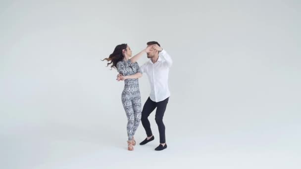 Concept d'amour, de relations et de danse sociale. Jeune beau couple dansant danse sensuelle sur fond blanc — Video