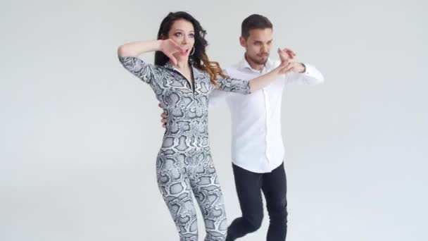 Concept of love, relationships and social dancing. Young beautiful couple dancing sensual dance on a white background — Stock Video