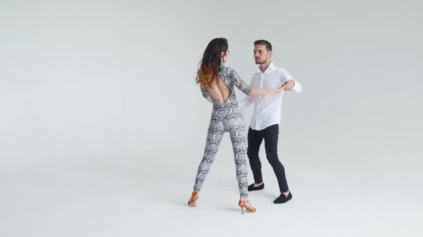 Concepto de amor, relaciones y baile social. Joven hermosa pareja bailando sensual danza sobre un fondo blanco — Vídeo de stock