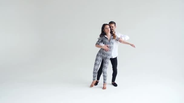 Concept d'amour, de relations et de danse sociale. Jeune beau couple dansant danse sensuelle sur fond blanc — Video