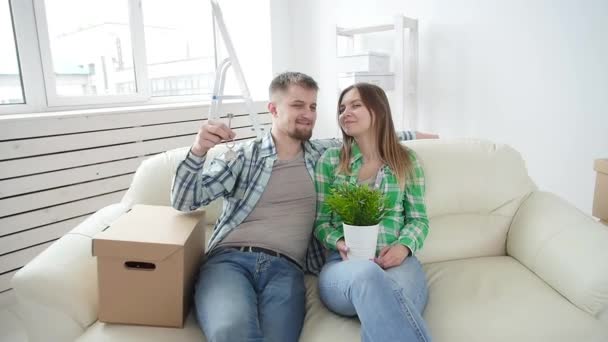 Konzept des Kaufs und der Vermietung von Immobilien. glückliches junges Paar zeigt Schlüssel für neues Zuhause — Stockvideo