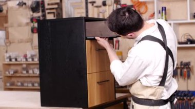 İş ve üretim kavramı. Atölye genç adam mobilya birleştirir