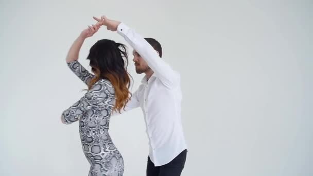 Concept d'amour, de relations et de danse sociale. Jeune beau couple dansant danse sensuelle sur fond blanc — Video