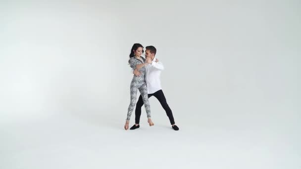 Concetto di amore, relazioni e danza sociale. Giovane bella coppia ballare danza sensuale su uno sfondo bianco — Video Stock