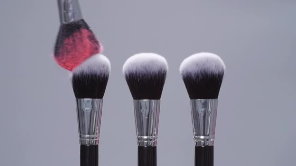 Pennello make-up con spruzzi di polvere rosa esplosione su sfondo grigio al rallentatore — Video Stock