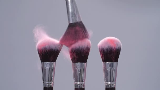Make-up borstel met roze poeder spatten explosie op grijze achtergrond op Slow Motion — Stockvideo
