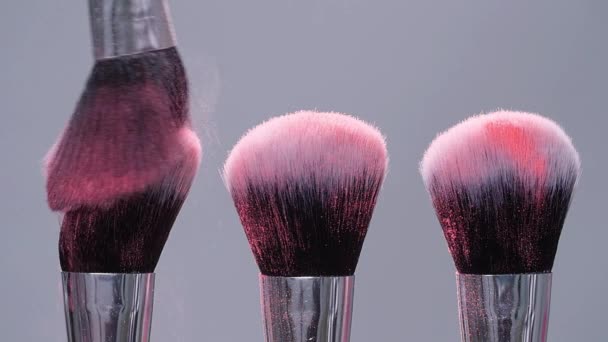 Szczotka do makijażu z różowym proszkiem rozpryskami wybuchu na szarym tle w zwolnionym tempie — Wideo stockowe