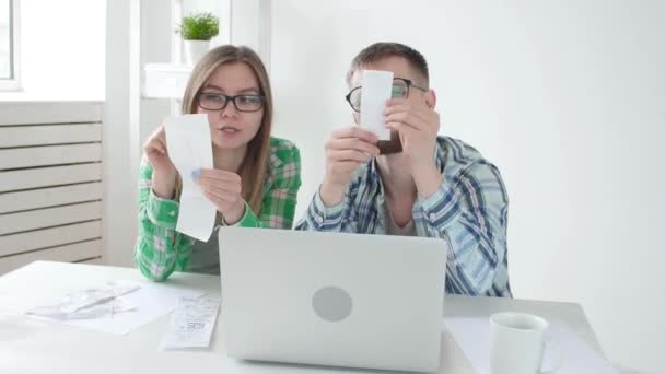 Marido e esposa contar compras e contas para o mês passado e gravar os resultados em sua contabilidade em casa em um caderno e em um laptop. Conceito de poupança e contabilidade — Vídeo de Stock