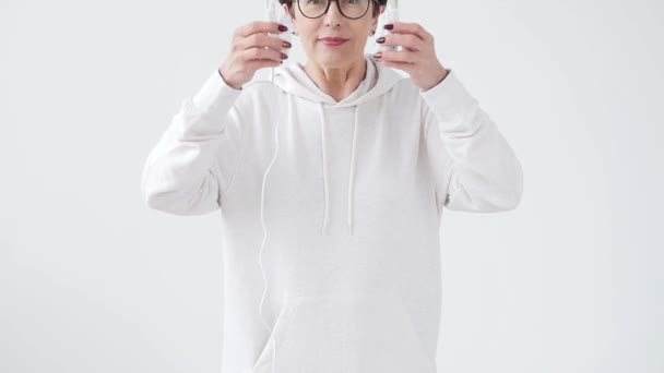 Hobby, los intereses y el concepto de la gente - Mujer hermosa 40-50 años de edad escuchando música en auriculares grandes — Vídeo de stock