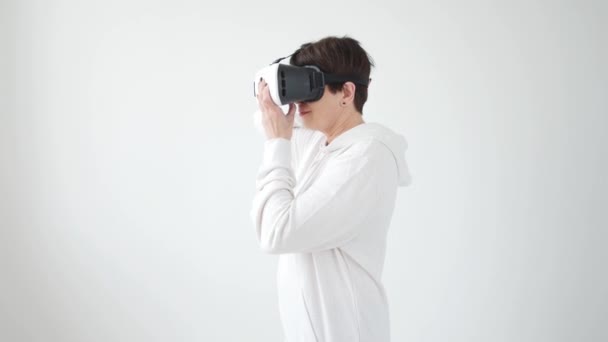 Femme d'âge moyen en pull blanc regardant un film avec des lunettes de réalité virtuelle. Le concept du futurisme et des nouvelles technologies . — Video