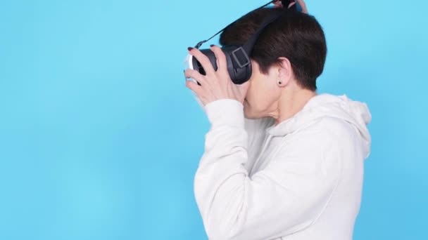 Vrouw van middelbare leeftijd in een witte trui kijken naar een film met een bril van Virtual Reality. Het concept van futurisme en nieuwe technologieën — Stockvideo