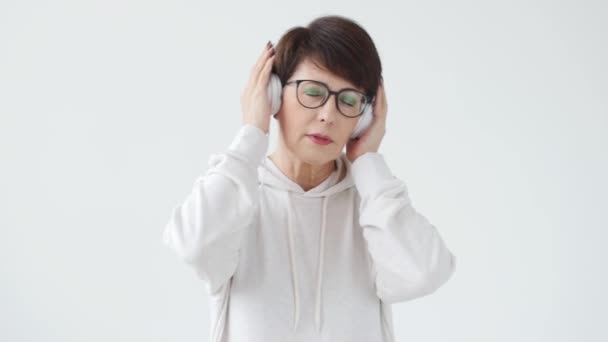 Hobby, interesses e conceito de pessoas - Mulher bonita 40-50 anos de idade ouvir música em fone de ouvido grande — Vídeo de Stock