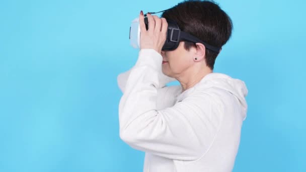 Medelålders kvinna i en vit tröja titta på en film med glasögon av virtuell verklighet. Konceptet Futurism och ny teknik — Stockvideo