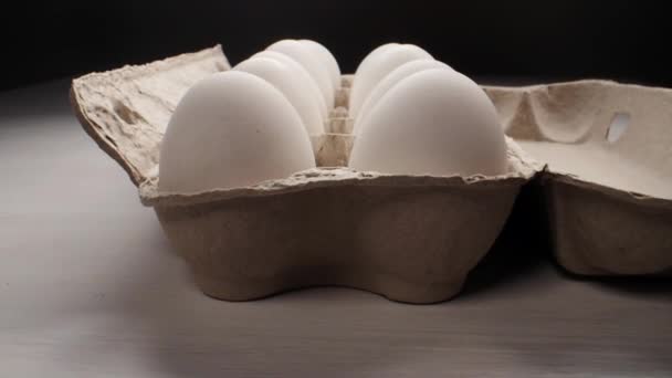 Сырое свежее яйцо в упаковке на белом, слайд-шот — стоковое видео