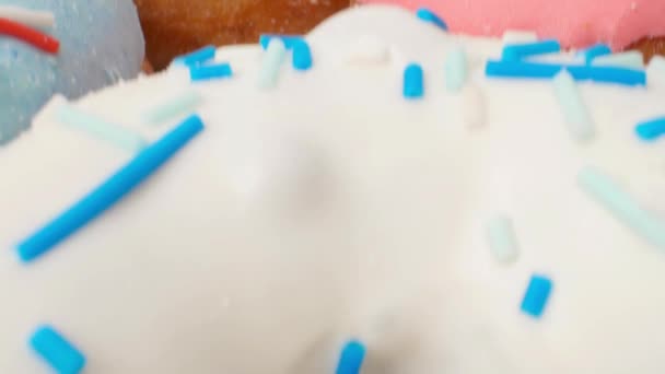 Deliziose ciambelle multicolori su uno sfondo bianco. Movimento dolly liscio — Video Stock