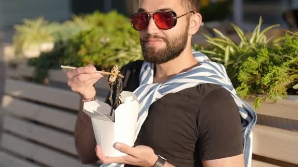 Fiatal szakállas arab vagy latin fiatal férfi étkezési utcai étel, kínai tészta — Stock videók