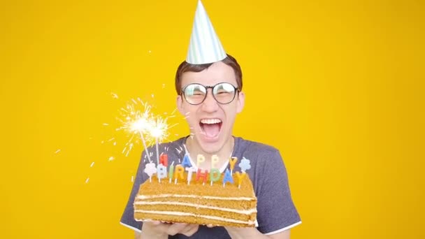 Happy Birthday Konzept. junger lustiger Mann mit einer Torte auf orangefarbenem Hintergrund — Stockvideo