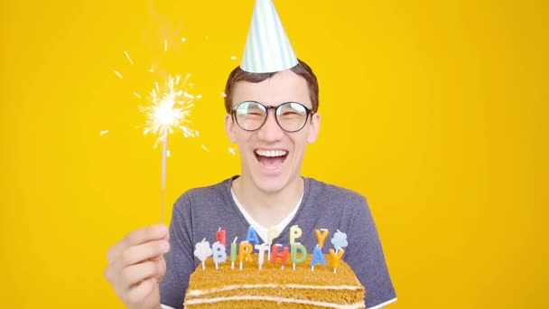 Feliz aniversário conceito. Jovem homem engraçado com um bolo o um fundo laranja — Vídeo de Stock