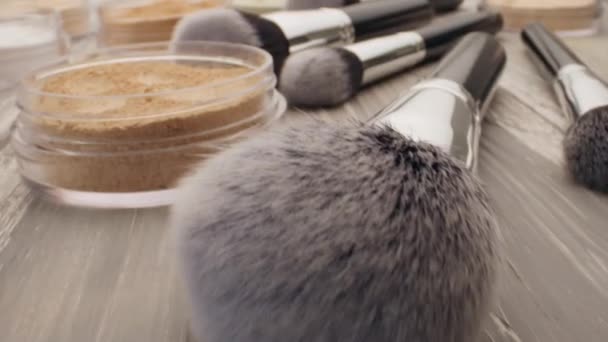 Cosméticos y concepto de belleza. Cepillo para maquillaje con polvo sobre una mesa de madera — Vídeo de stock