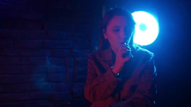 Молодая женщина в неоновом красно-синем дыму с парой или электронными сигаретами — стоковое видео