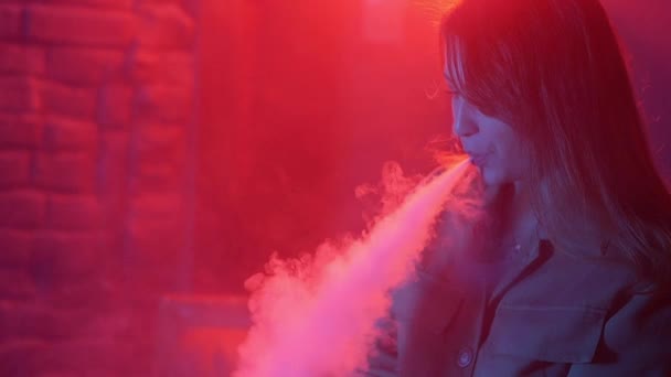 Giovane donna in neon rosso e blu fumo con vaporizzatore o e-sigarette — Video Stock