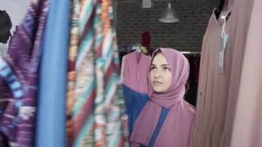 Mağazada kıyafet seçen genç bir Müslüman kadın