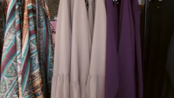 Молодая мусульманка выбирает одежду в магазине — стоковое видео