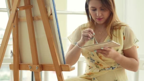 Artista femenina trabajando en su taller, creando un cuadro hermoso, pintando con coloridos óleos. Mujer pintor dibujo sobre lienzo — Vídeos de Stock