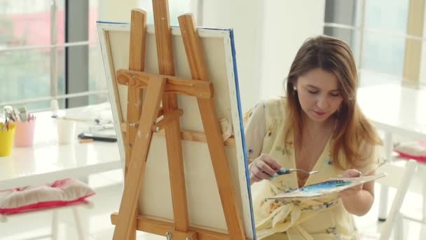 Vrouwelijke kunstenaar werkt bij haar workshop, het creëren van mooie foto, schilderen met kleurrijke oliën. Vrouw schilder tekening op doek — Stockvideo