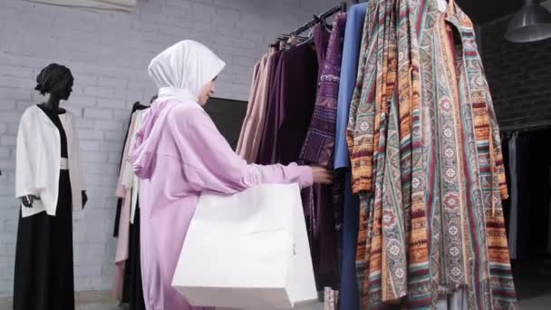 Młoda muzułmańska kobieta wybiera ubrania w sklepie — Wideo stockowe