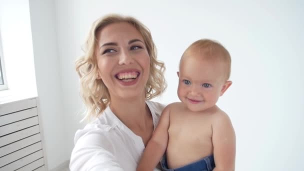 Концепция семьи и материнства - счастливая молодая мама с маленьким ребенком делает селфи — стоковое видео