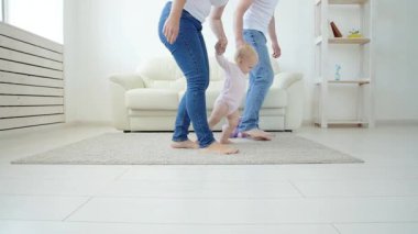 Beyaz güneşli oturma odasında yürümeyi öğrenen bebek bebek ilk adımları. Çocuk için ayakkabı.