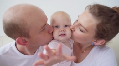 Mutlu aile konsepti. Anne-babalar gülümseyerek bebek öpüşme.