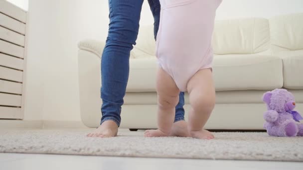 Baby het nemen van de eerste stappen met moeders helpen thuis — Stockvideo