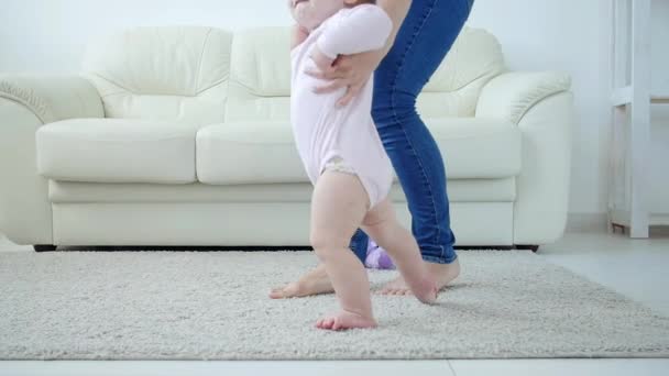 Младенец делает первые шаги с помощью матери на дому — стоковое видео