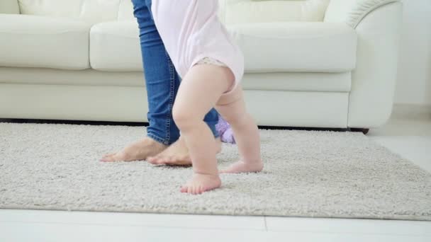 Baby het nemen van de eerste stappen met moeders helpen thuis — Stockvideo