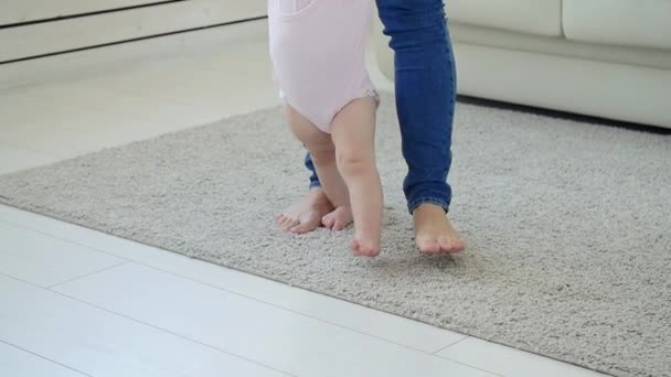 Младенец делает первые шаги с помощью матери на дому — стоковое видео