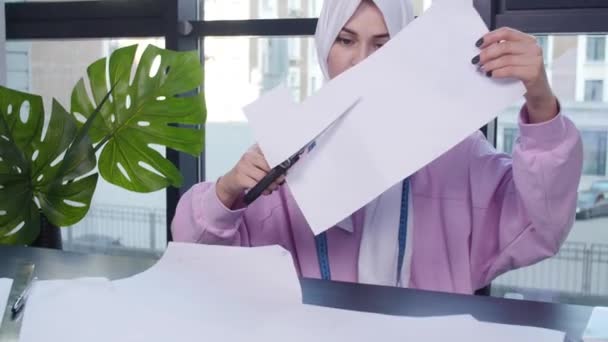 Küçük işletme ve hobi konsepti. Müslüman kadın moda tasarımcısı terzi dükkanında masada kağıt desen sabitleme — Stok video