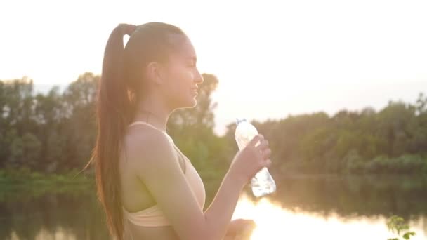 若い女性ジョガーは、トレーニング後に水を飲みます — ストック動画
