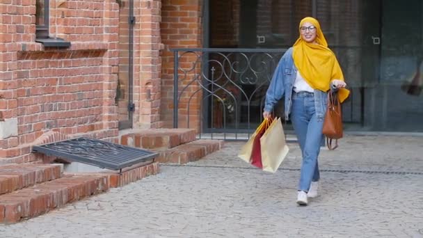 Einkaufskonzept. Stilvolles muslimisches Mädchen spaziert mit Einkaufsbummel durch die Stadt — Stockvideo