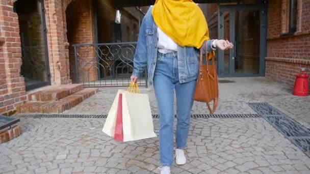 Mujer musulmana bastante joven con la celebración de bolsas de compras después de comprar — Vídeos de Stock