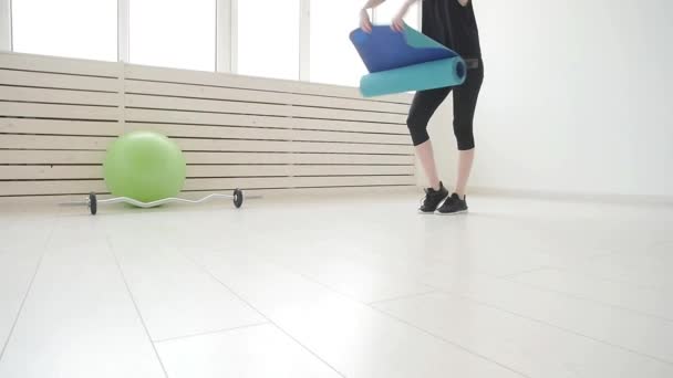 Conceito de esportes e saúde e relaxamento. Jovem com um tapete de ioga e exercícios em um apartamento ou ginásio — Vídeo de Stock